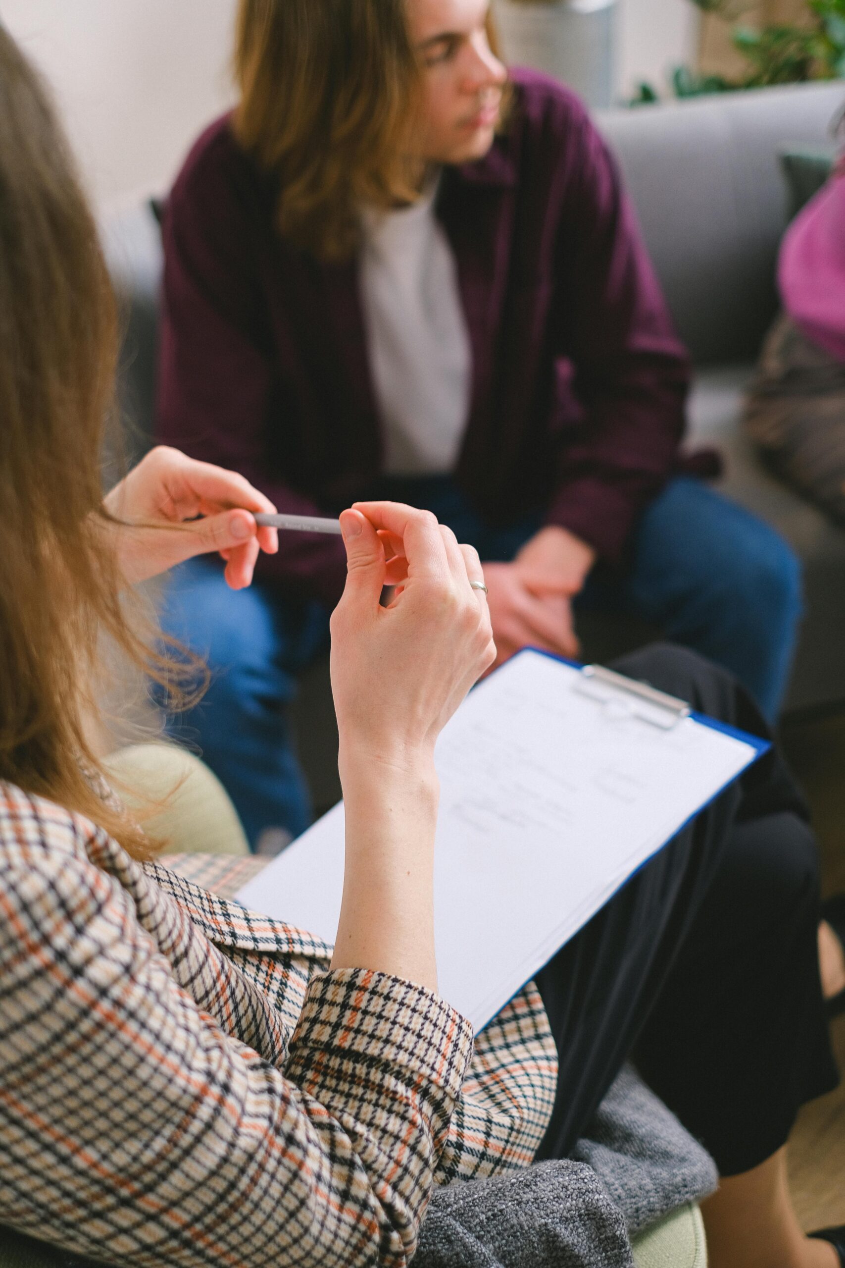 A therapist with a clipboard conducting a counseling session with clients.